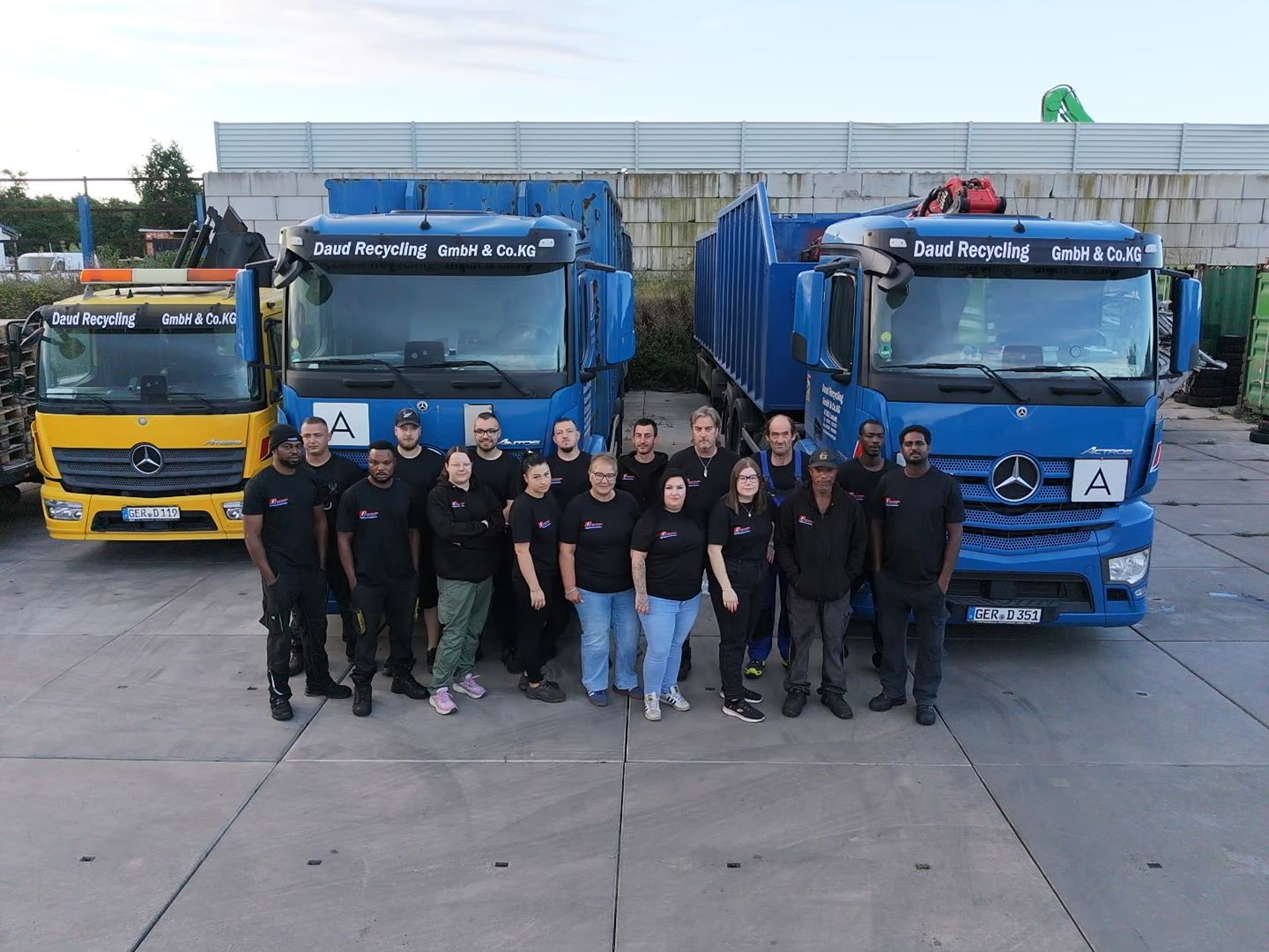 Das Team von Daud Recycling vor zwei Lkw und dem Abschleppwagen auf dem Betriebshof